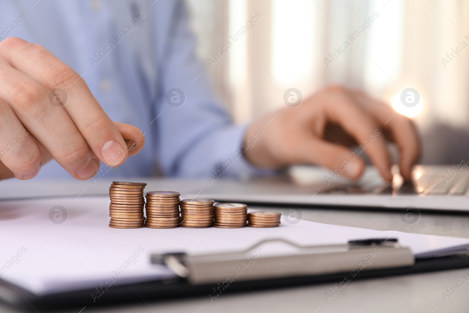 Photo of Man stacking coins at table indoors, closeup