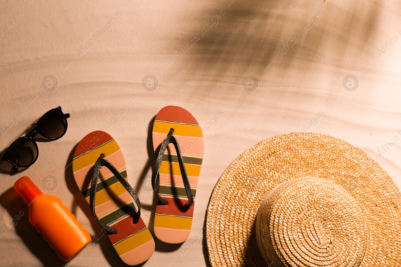 Photo of Different beach accessories on sand, flat lay