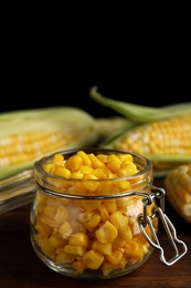 Tasty sweet corn kernels in jar on wooden table