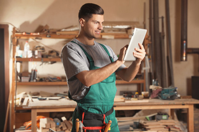 Professional carpenter with tablet in modern workshop