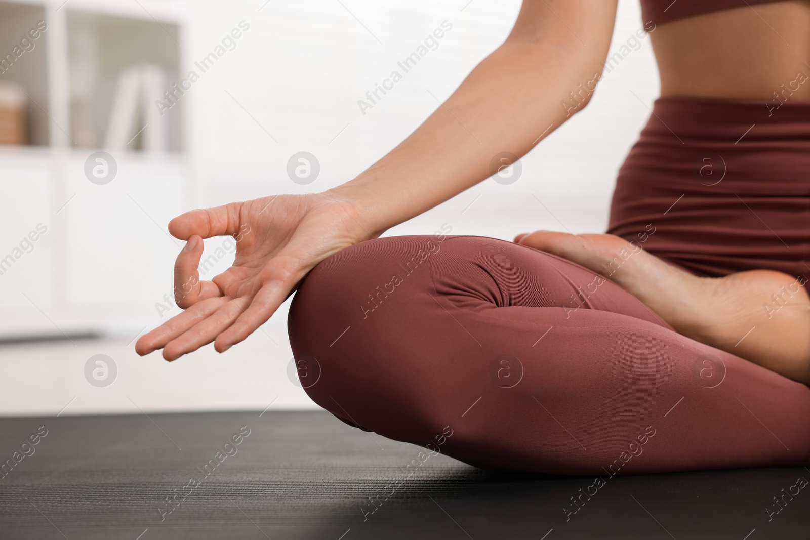 Photo of Woman practicing Padmasana on yoga mat at home, closeup. Lotus pose