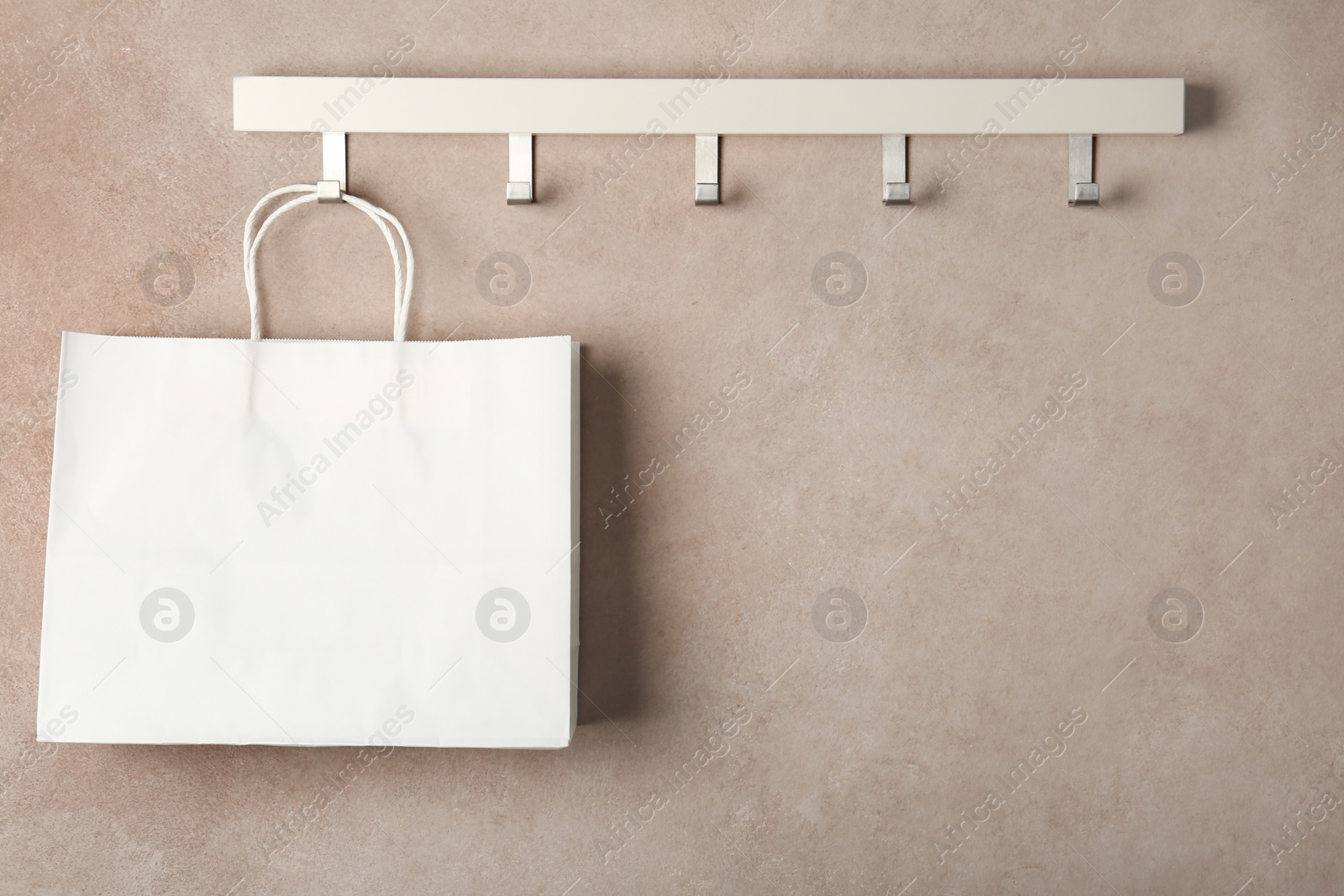 Photo of Rack with paper shopping bag on color wall