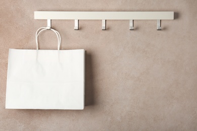 Photo of Rack with paper shopping bag on color wall