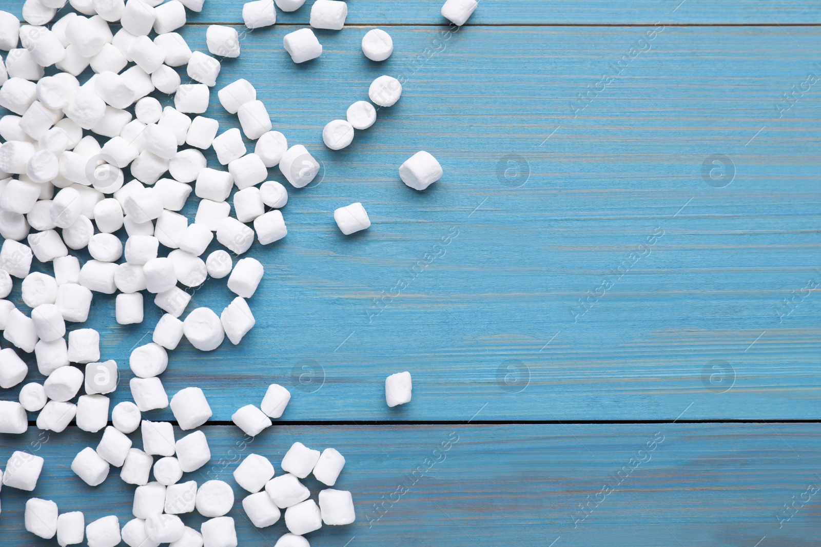 Photo of Delicious marshmallows on light blue wooden table, flat lay. Space for text