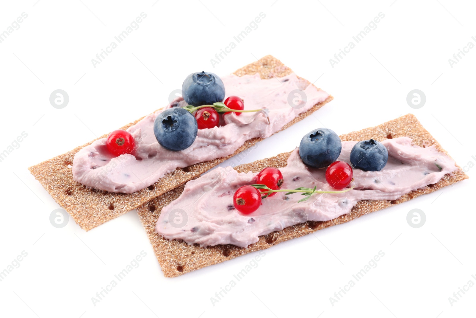 Photo of Tasty cracker sandwiches with cream cheese, blueberries, red currants and thyme on white background