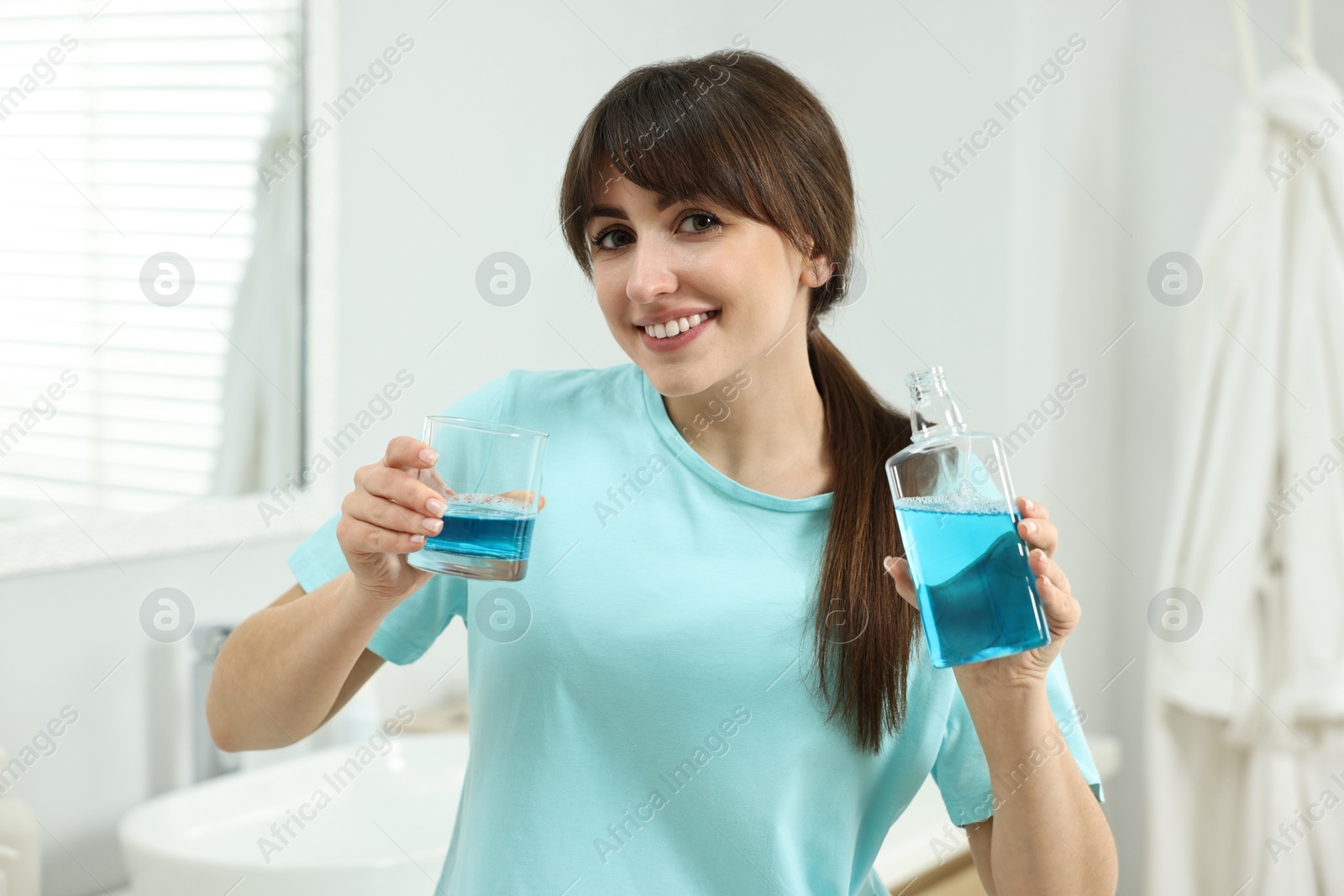 Photo of Young woman with mouthwash in bathroom. Oral hygiene