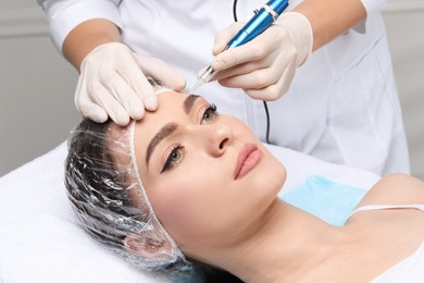 Photo of Young woman during procedure of permanent eyebrow makeup in beauty salon, closeup