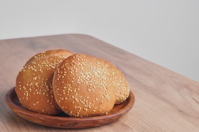 Photo of Fresh buns with sesame seeds on wooden table. Space for text