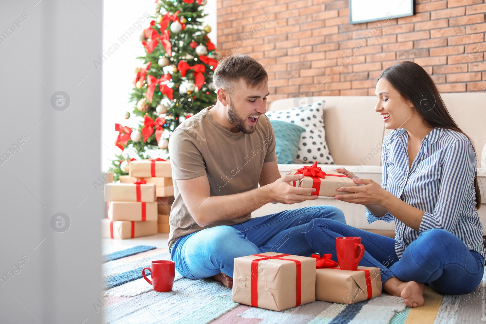 Photo of Happy young couple with Christmas gifts at home