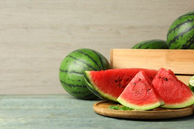 Photo of Delicious ripe whole and cut watermelons on wooden table, space for text