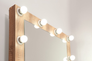 Mirror with light bulbs on white wall, closeup. Dressing room