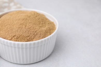 Photo of Dietary fiber. Psyllium husk powder in bowl on light grey table, closeup
