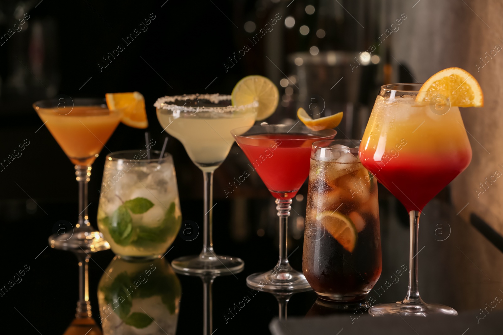 Photo of Different delicious cocktails on black table in bar