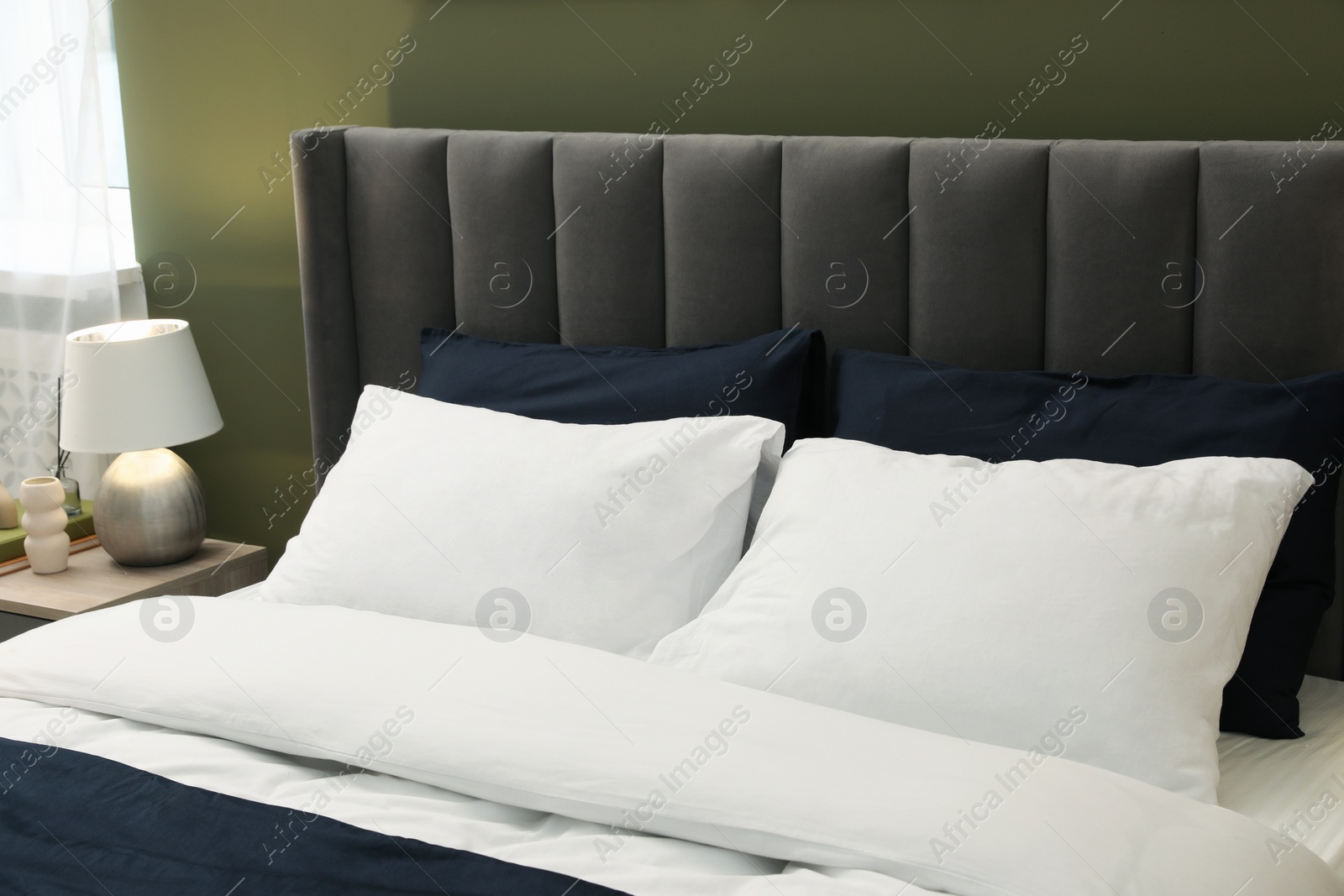 Photo of Comfortable bed with soft pillows in stylish room. Interior design