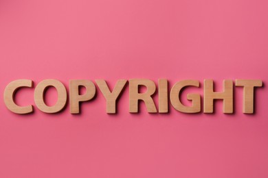 Photo of Word Copyright made of wooden letters on dark pink background, flat lay. Plagiarism concept