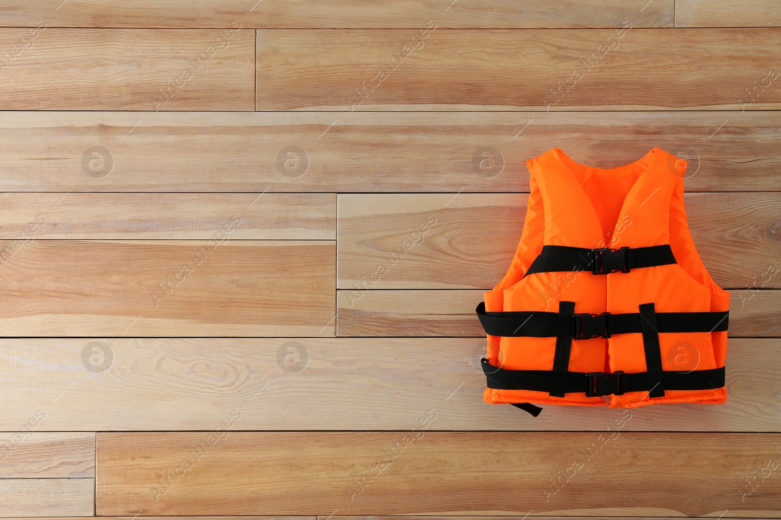 Photo of Orange life jacket on wooden background. Space for text