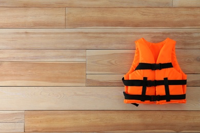 Photo of Orange life jacket on wooden background. Space for text