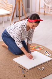 Photo of Happy woman artist drawing picture on canvas indoors