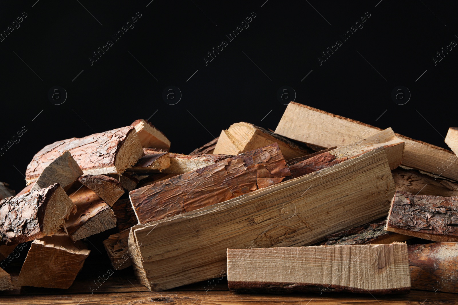 Photo of Cut firewood on table against black background