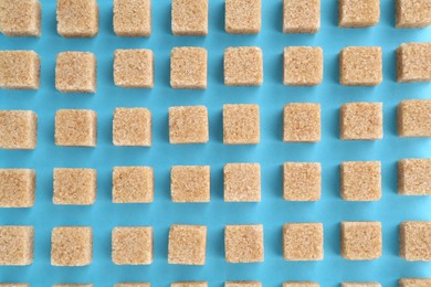 Photo of Brown sugar cubes on light blue background, top view