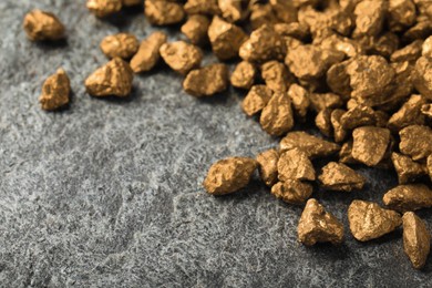 Photo of Pile of gold nuggets on grey table, space for text