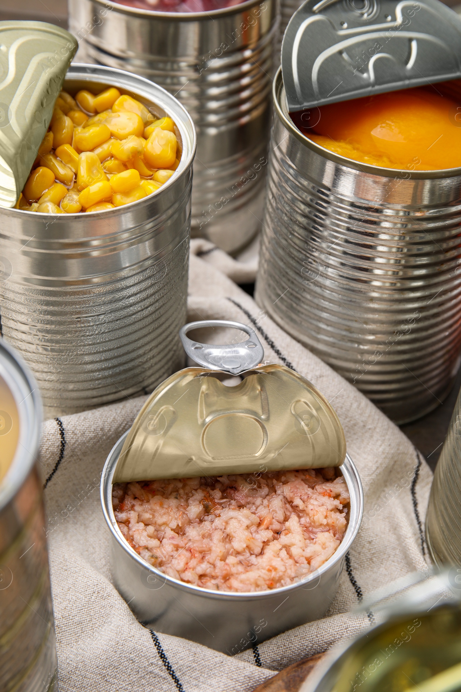 Photo of Open tin cans with shrimps and different products on table