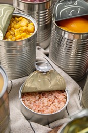 Photo of Open tin cans with shrimps and different products on table