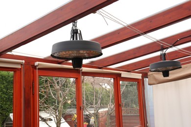 Photo of Stylish hanging infrared heaters on terrace indoors