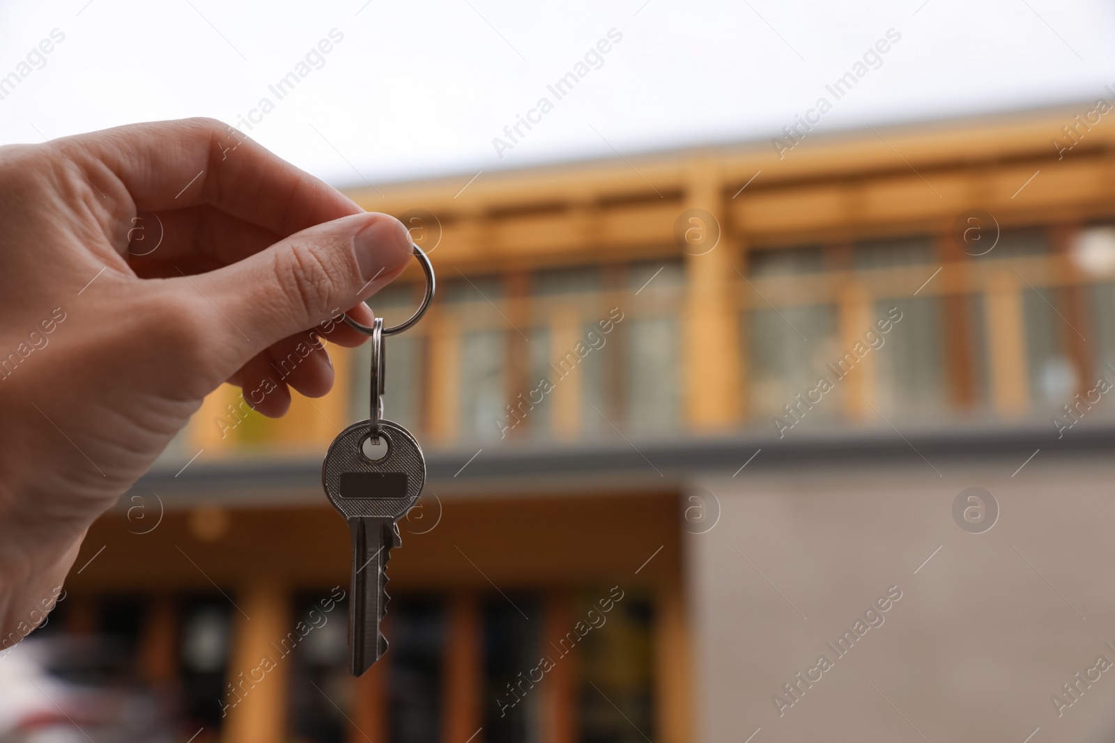 Photo of Real estate agent holding keys to new house outdoors, closeup. Space for text