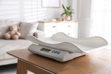 Photo of Modern digital baby scales on wooden table in room