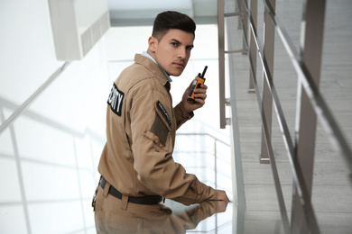 Professional security guard with portable radio set on stairs