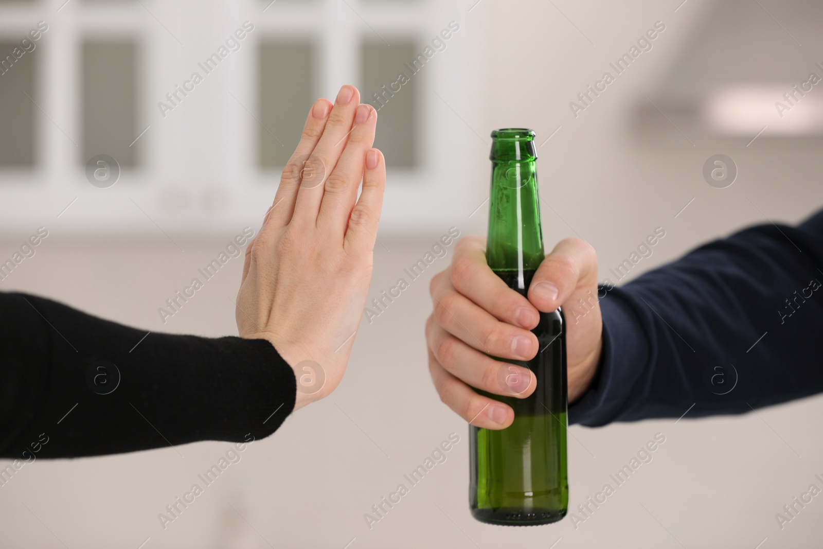 Photo of Woman refusing to drink beer in kitchen, closeup. Alcohol addiction treatment