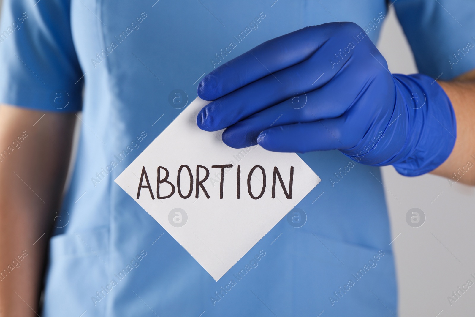 Photo of Doctor holding paper card with word ABORTION, closeup