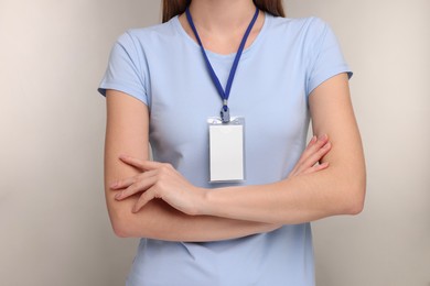 Woman with blank badge on grey background, closeup