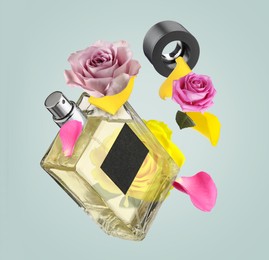 Bottle of perfume and roses in air on grey background. Flower fragrance