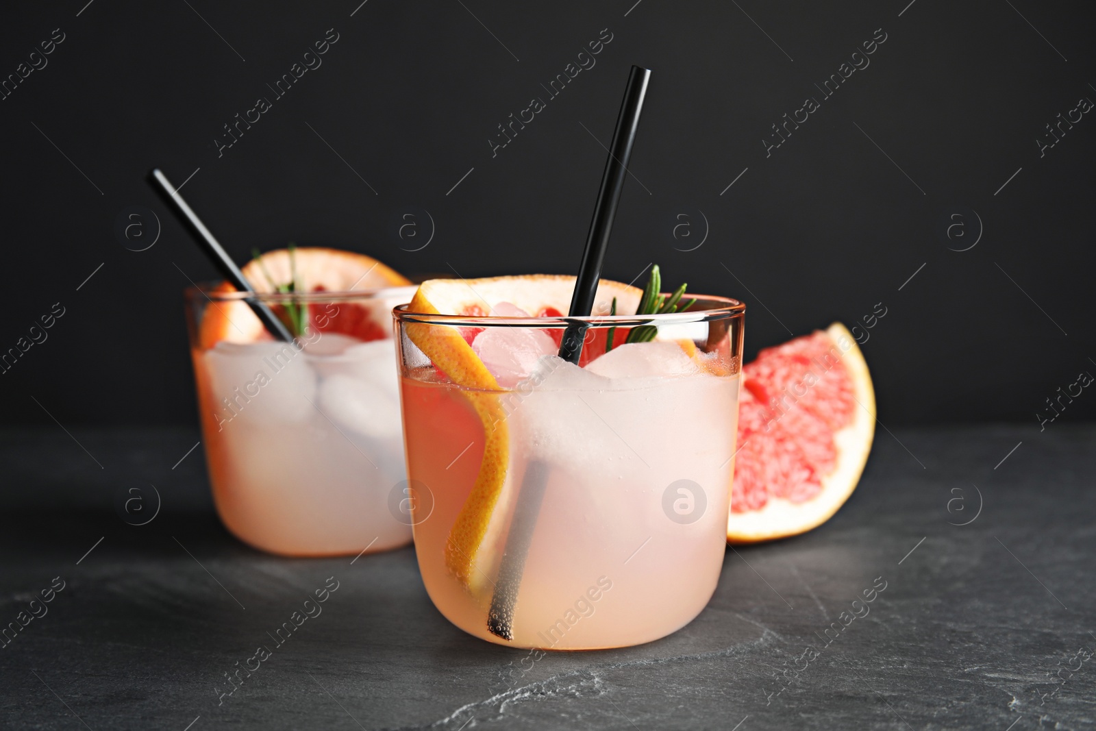 Photo of Glasses of cocktail and grapefruit slice on table, closeup