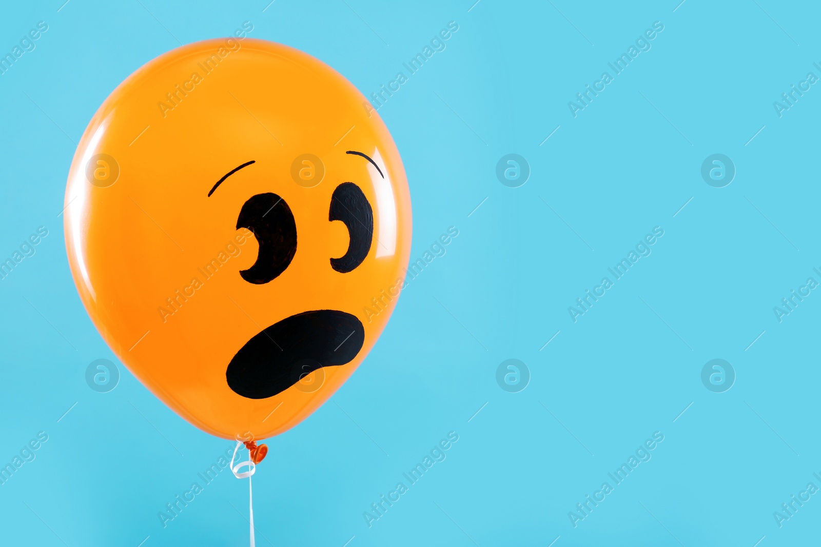 Photo of Orange balloon with drawing of scared face on blue background, space for text. Halloween party