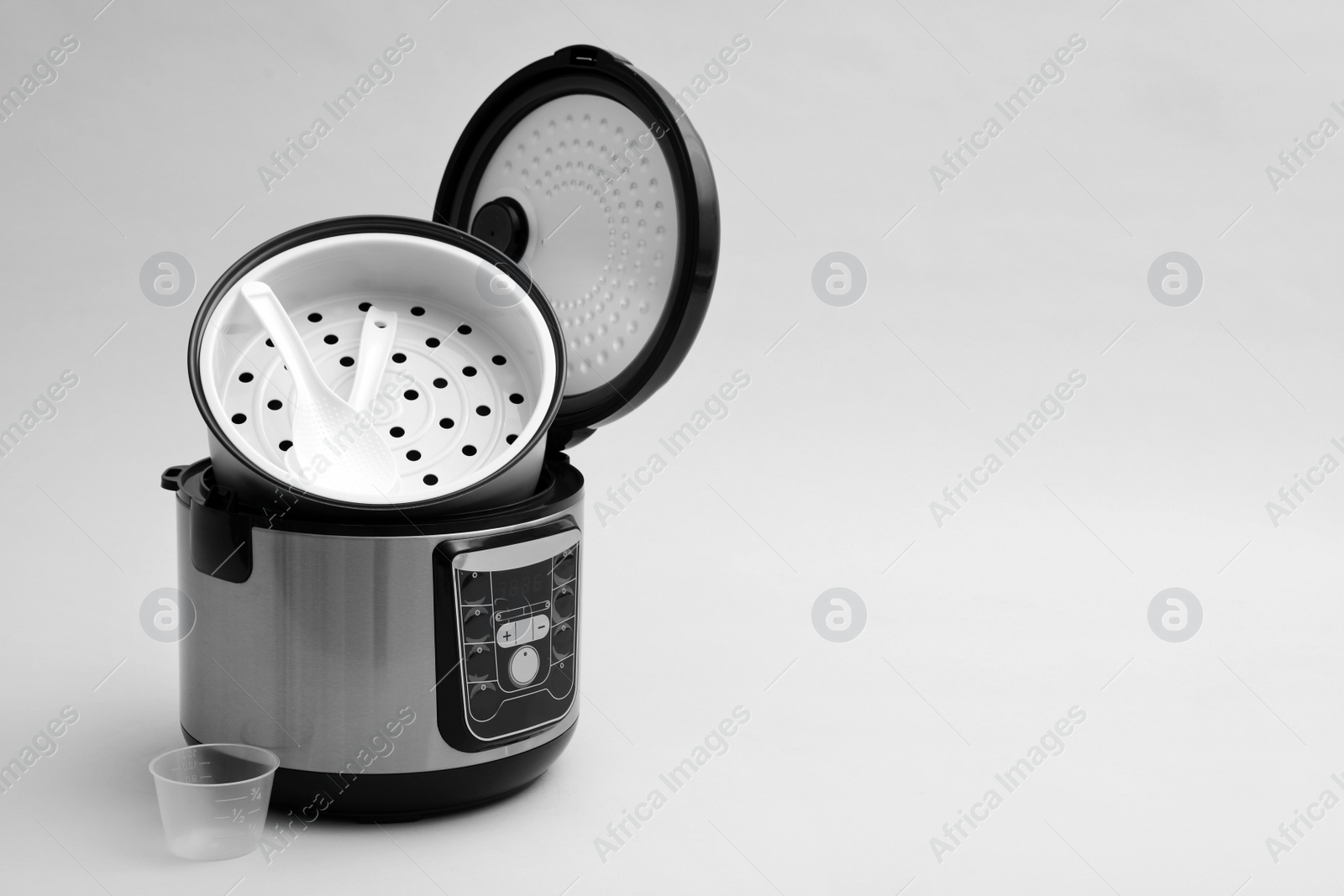 Photo of Modern electric multi cooker, parts and accessories on grey background. Space for text