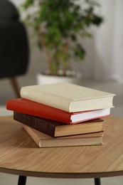 Photo of Stack of different hardcover books on wooden table indoors