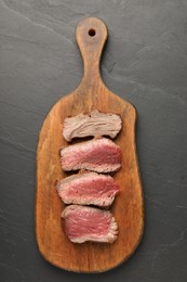 Photo of Delicious sliced beef tenderloin with different degrees of doneness on black table, top view