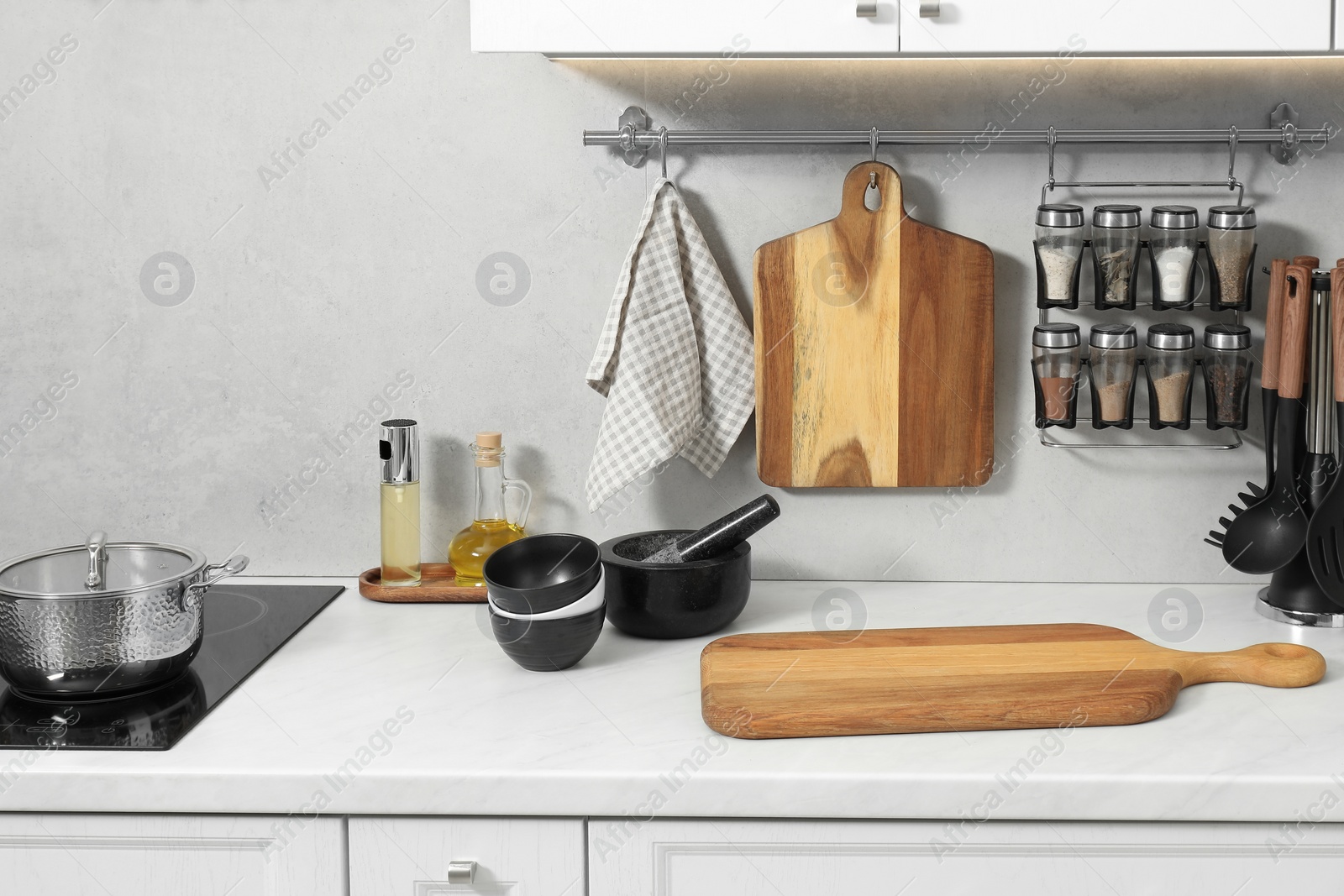 Photo of Wooden cutting boards and other cooking utensils on white countertop in kitchen