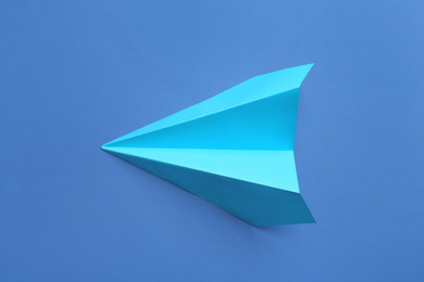 Paper plane on blue background, top view