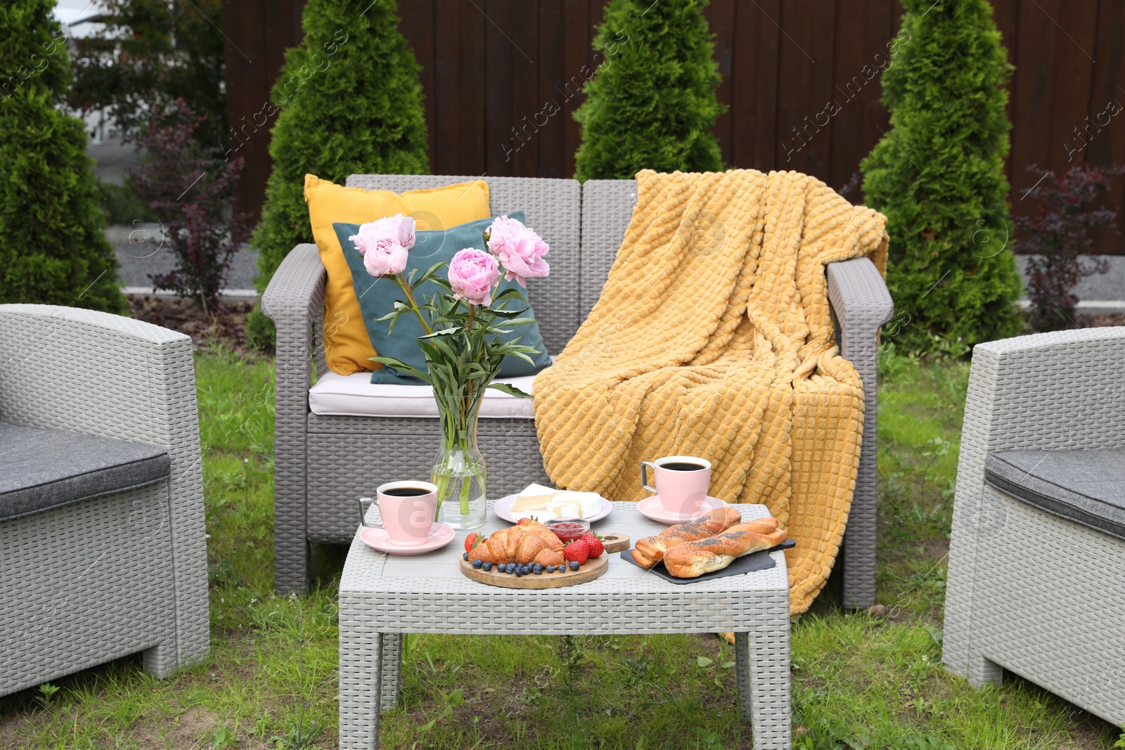 Breakfast served outdoors. Morning drink, food and vase with flowers on rattan table Photo of Breakfast served outdoors. Morning drink, food and vase with flowers on rattan table