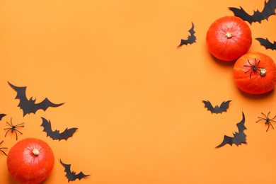 Photo of Flat lay composition with pumpkins, paper bats and spiders on orange background, space for text. Halloween decor