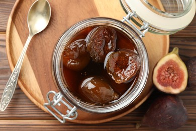 Photo of Jar of tasty sweet jam and fresh figs on wooden table, flat lay