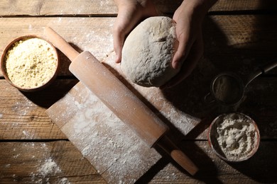 Photo of Man making dough at wooden table, top view