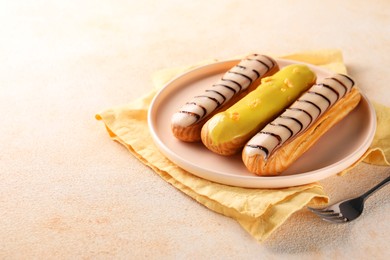 Photo of Different tasty glazed eclairs served on color textured table. Space for text