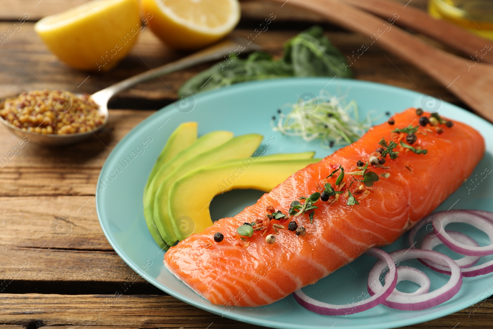 Photo of Delicious fresh salmon with spinach, avocado and onion served on wooden table