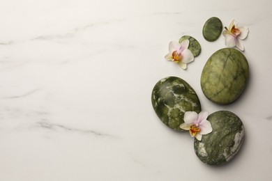 Photo of Flat lay composition with spa stones and orchid flowers on white marble table. Space for text