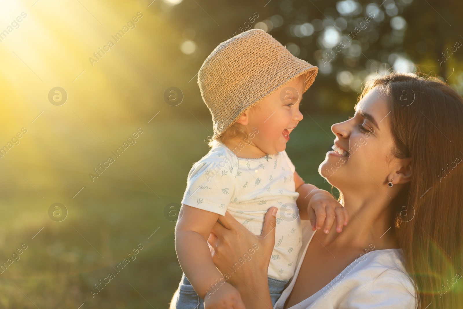 Photo of Happy mother with her cute baby daughter in park on sunny day. Space for text